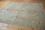 Hand knotted Afghani Caucasian design rug close-up: geometric border, stylized birds in ivory, turquoise, beige.