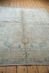 Ivory and beige Afghani Caucasian rug end showing turquoise geometric motifs and short fringe.