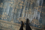 Distressed vintage Oushak carpet featuring blue, ivory floral sprays and mostly even wear.