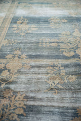 Vintage distressed Oushak carpet with prominent floral sprays and varied blue and beige texture.