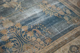 Close-up of a distressed Oushak carpet, showcasing dark blue field and ivory floral sprays.