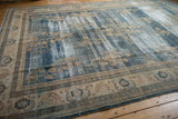 Distressed vintage Oushak carpet, showing beige border with floral pattern and worn blue field.