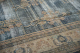 Distressed Oushak carpet detail: faded dark blue floral field and contrasting beige border.
