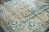 Angled view of the distressed Oushak's faded denim blue border and floral field.