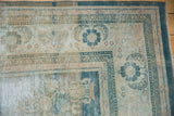 Curvilinear floral sprays and dark ocean blue borders on a distressed vintage Oushak rug corner.