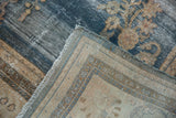 Distressed vintage Oushak carpet corner showing worn dark blue floral pile and beige reverse.