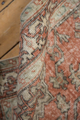 Close-up of the rolled edge of a vintage distressed Sivas rug, showing terra cotta and beige textured pile.