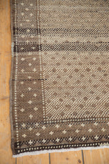 Distressed hand-knotted Oushak rug corner with speckled diamond motifs and fringed edge.