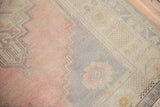 Oushak rug detail showcasing distressed dusty rose, slate gray stepped contour, and ivory pattern.