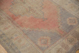 Detail of distressed vintage Oushak rug with dusty rose field, pale gray stepped contour, ivory spandrel.