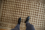 Distressed vintage Oushak rug featuring abrashed coffee brown diamond lattice and subtle floral guls.