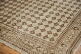 Corner of a distressed Oushak rug showing geometric border and faded diamond lattice.