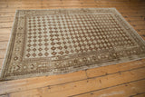 Distressed corner of a vintage Oushak rug showing lattice diamond guls and worn coffee brown border.