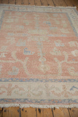 Distressed Oushak rug pile texture showing blush, ivory, and dusty blue floral vinery with wear.