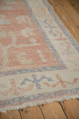 Distressed fringe and geometric border details in blush, ivory, and dusty blue from vintage Oushak rug.