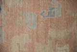 Distressed Oushak rug pile texture showing blush, ivory, and dusty blue motifs.