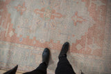 Distressed texture of a vintage Turkish Oushak rug with blush, powder blue, and ivory Samovar motifs.