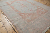 Distressed vintage Oushak rug, showing even wear with blush and pale blue Samovar design.