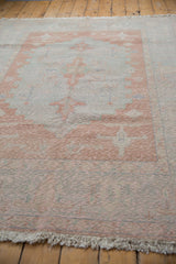 Textured pile and intact fringe of a distressed vintage Oushak rug with blush and pale blue Samovar motifs.