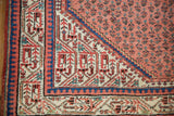 Corner of Vintage Mir Sarouk rug, featuring madder red field and ivory pawn, vine borders.