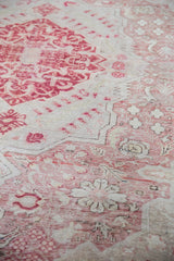Close-up: Distressed Oushak rug with pale cherry red floral motifs, ivory field, and visible foundation.