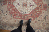Overhead view showing the worn texture and geometric medallion of a vintage blush Oushak carpet.