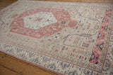 Angled view of a vintage Oushak carpet showing the blush medallion and beige floral field.