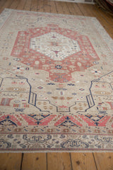 Angled view along the distressed Oushak carpet, highlighting its low-pile texture and blush medallion.