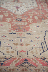 Angled view of the even wear and low pile on a distressed Oushak carpet in blush and beige.