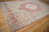 Angled perspective of a vintage Oushak carpet highlighting its distressed texture and blush medallion.