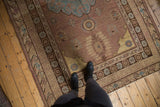 Distressed vintage Khotan carpet showing even wear, aqua blue and copper floral motifs underfoot.