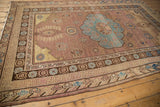 Distressed Khotan carpet corner detail, showcasing faded aqua blue floral motifs and rich geometric borders.