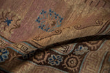 Distressed Khotan carpet's textured pile, showcasing stylized aqua blue and muted chestnut brown floral patterns.
