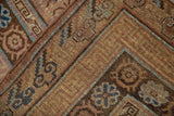 Distressed vintage Khotan carpet corner detailing geometric motifs and faded aqua, brown tones.