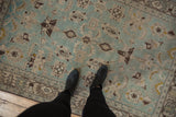 A person's perspective looking down at the distressed texture of the vintage Hamadan rug.
