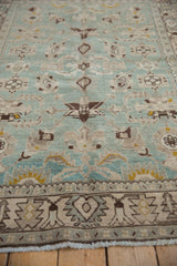 Low angle showing the even wear and geometric motifs on a vintage seafoam green rug.