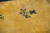 Detail of vintage Peking carpet: saffron yellow field with dark pictorial plant motifs.