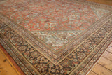 Corner of distressed Mahal carpet, terra cotta field with charcoal and ivory floral borders.