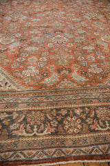 Vintage Mahal carpet's worn terra cotta field, blue floral vinery, and charcoal border details.