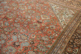 Distressed vintage Mahal rug corner, terra cotta field with floral vines and patterned borders.