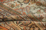 Folded section of distressed Mahal carpet, showcasing worn pile and faded floral vinery.
