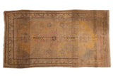 Vintage distressed Khotan carpet, saffron yellow, charcoal, with roundel medallion and scrolling clouds.