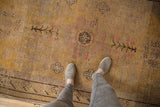 Worn saffron yellow Khotan rug featuring faded blush and charcoal roundel medallion motif.