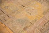 Distressed vintage Khotan carpet showing worn pile, saffron yellow, blush, beige, and charcoal motifs.