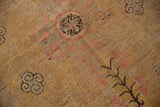 Distressed Khotan carpet detail: saffron field, charcoal scrolling clouds, and faded blush patterns.