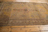 Distressed Khotan carpet detail, highlighting the worn saffron yellow pile and charcoal brown border.