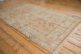 Vintage distressed Khotan rug with visible wear, soft beige, sand, and pale blush tones.