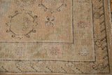 Vintage distressed Khotan rug corner, showing beige, brown, and blush geometric patterns with visible knot heads.