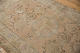 Distressed Khotan rug's pale saffron and blush minor medallion with infinity knot contour.