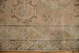 Distressed vintage Khotan rug corner, showing worn pile with visible foundation texture.